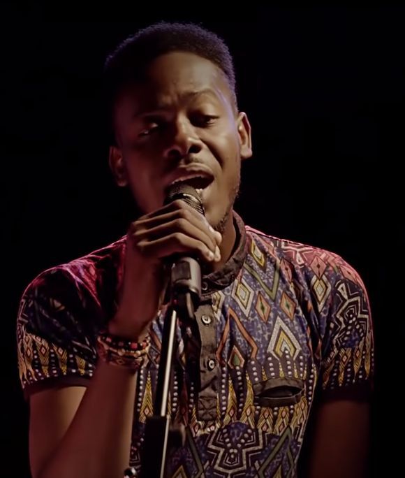 Adekunle Gold singing into a microphone