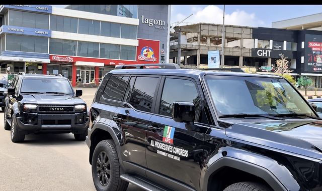 Black Toyota Prado SUVs, one branded "All Progressives Congress, Government House Abuja", parked on a street in Abuja