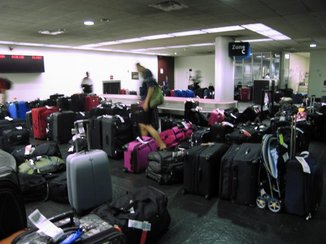 Suitcases lined up in an airport baggage hall (stock image)